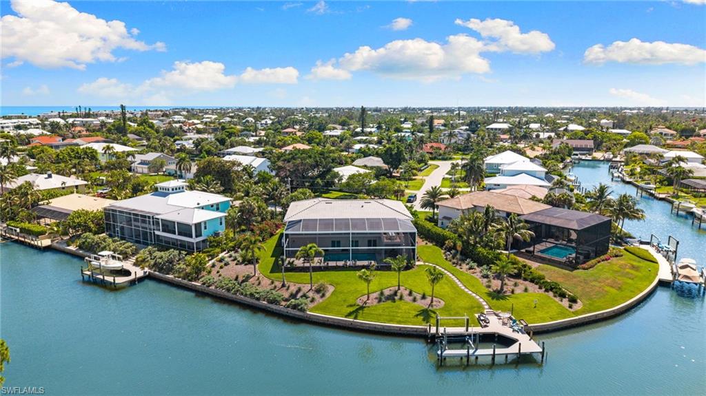 Waterfront property featuring a private boat dock, lush green lawns, and mature landscaping