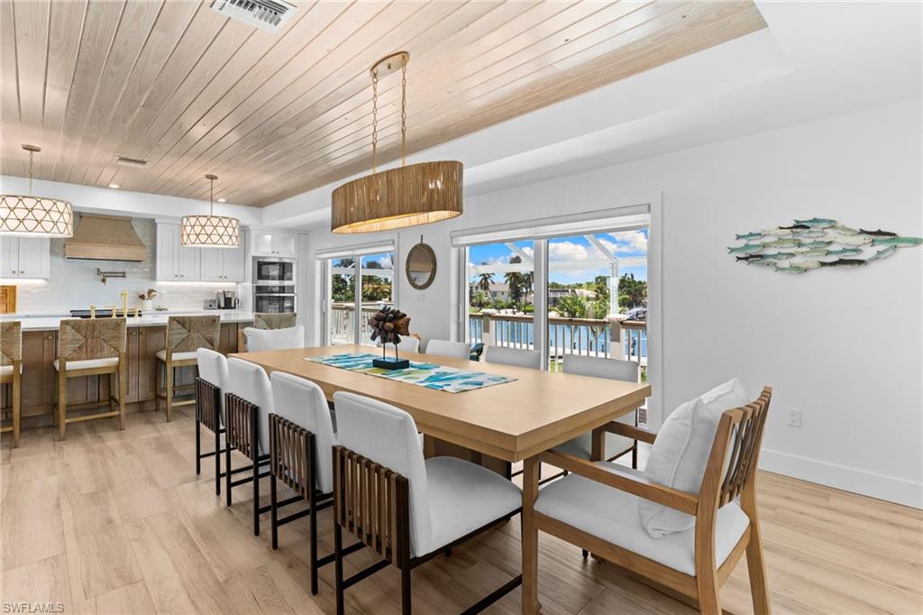Open-concept dining area featuring wood-finish flooring, a wood plank ceiling, and a large dining table