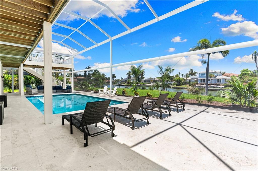 Screened outdoor living area with a rectangular pool, extensive paver patio, and water frontage