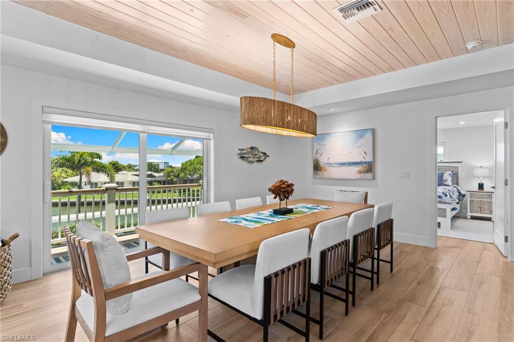 Dining area featuring wood-finish flooring, a wood plank ceiling, and a large sliding glass door opening to a waterway
