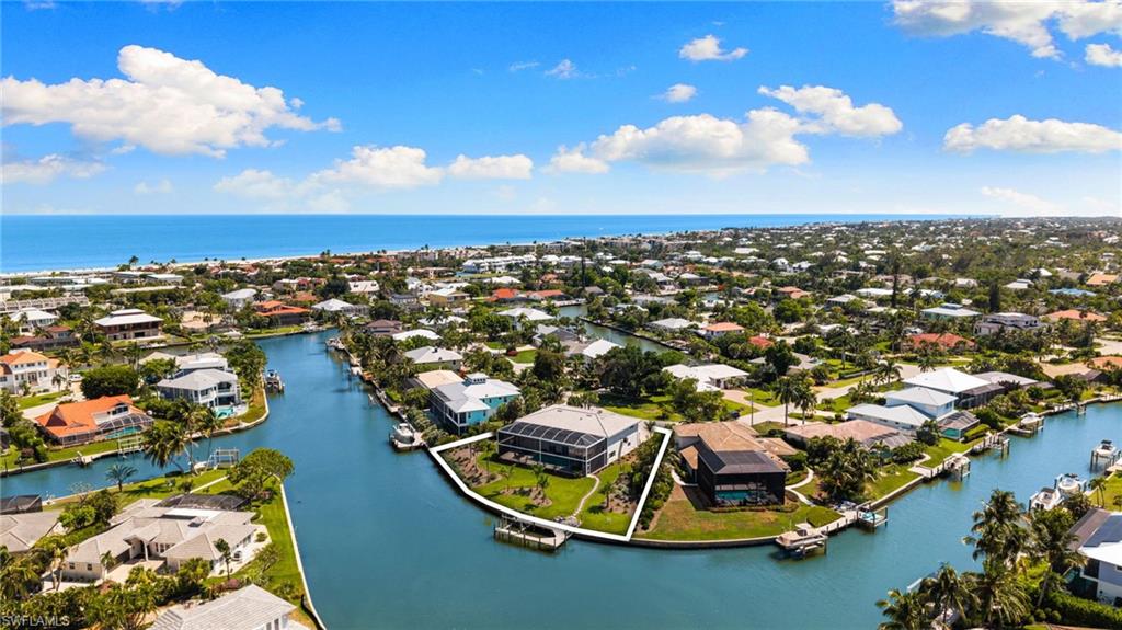 Waterfront property with direct Gulf access, featuring a private boat dock, screened lanai, and lush landscaping