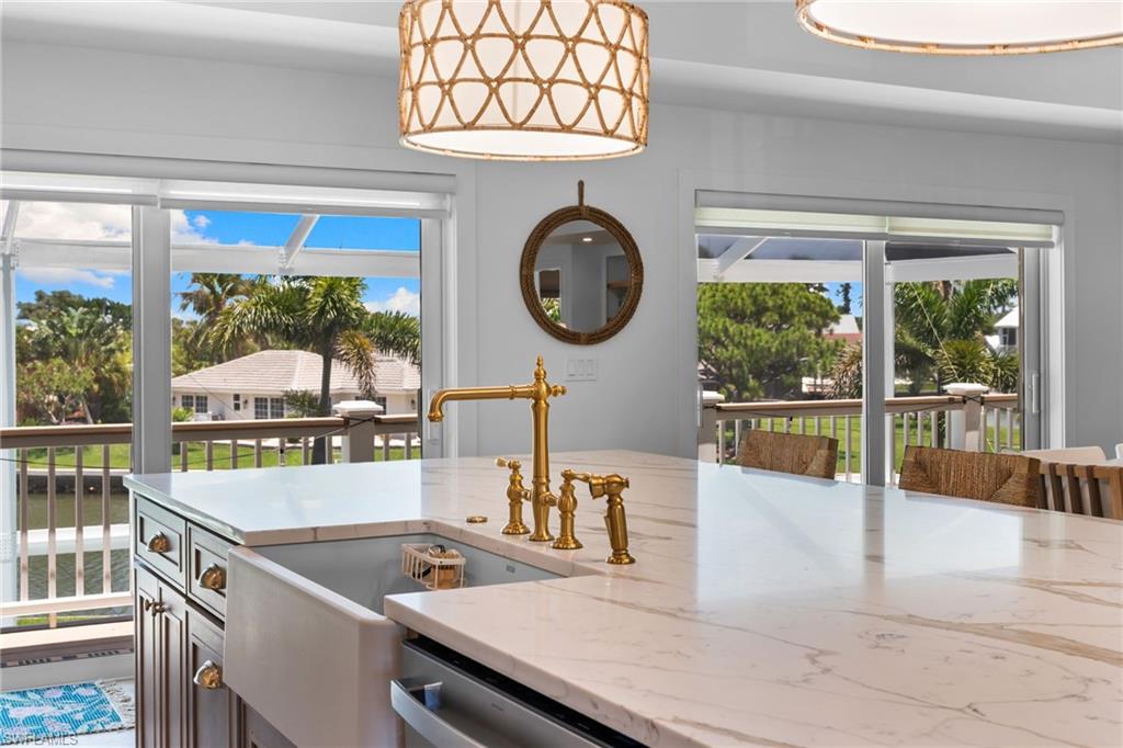 Kitchen island with white marble-finish countertop, farm sink, and gold-finish faucet