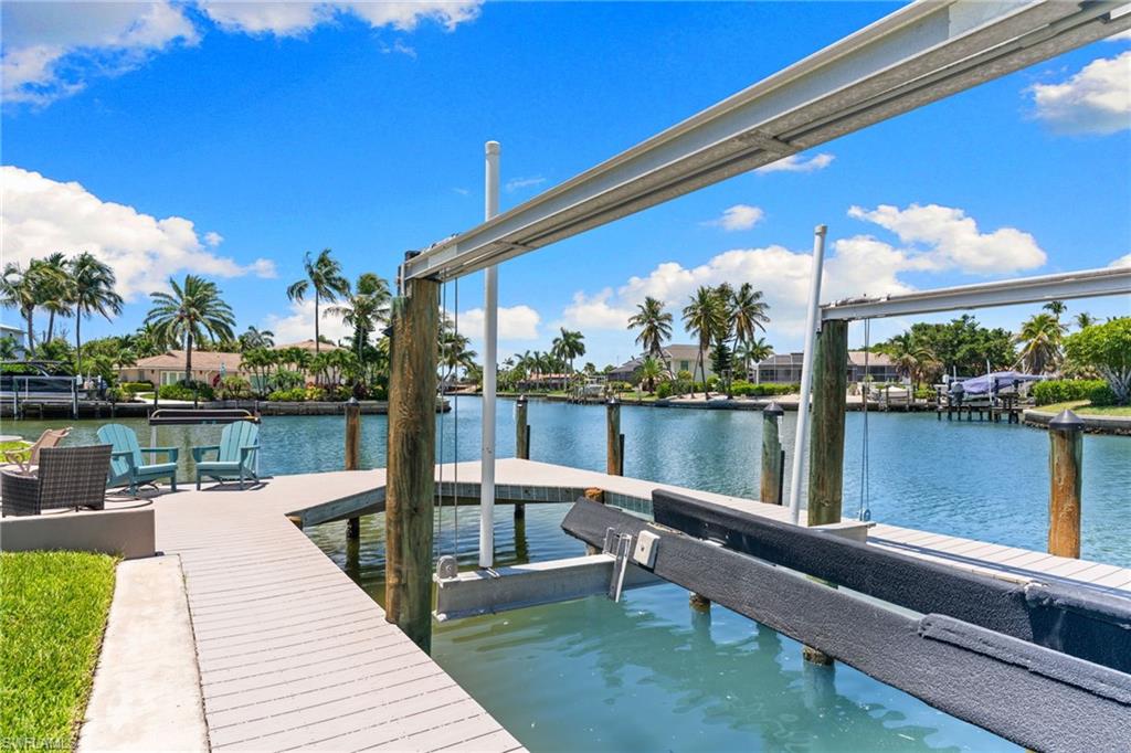 Waterfront property featuring a private boat lift, a composite wood dock, and a paver patio area
