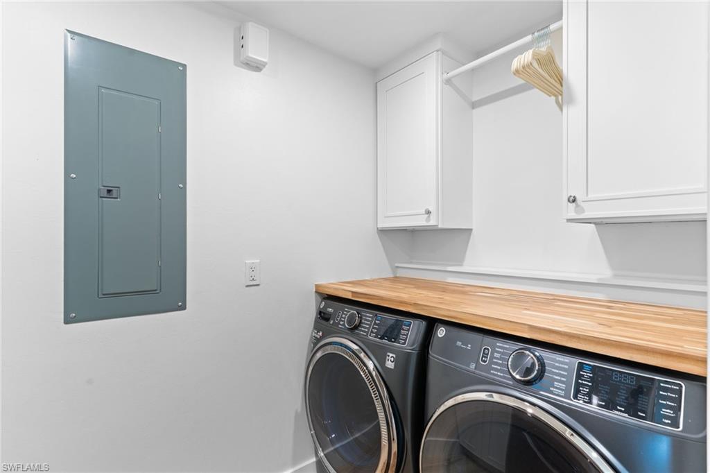 Dedicated laundry area featuring a wood-finish countertop, white cabinetry with silver hardware, and a built-in hanging rod