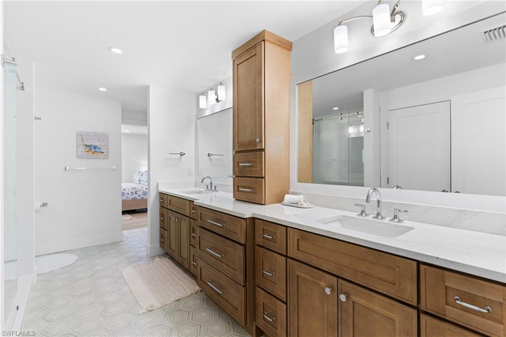 Dual vanity with light wood cabinetry and white countertops, featuring integrated sinks and brushed nickel fixtures