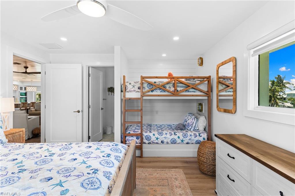 Well-lit room featuring shiplap accent wall, wood-finish flooring, and white ceiling fan