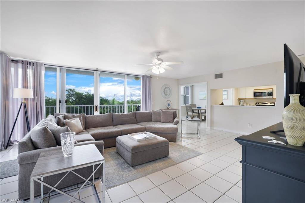 Living room with ceiling fan, french doors, floor to ceiling windows, and light tile flooring