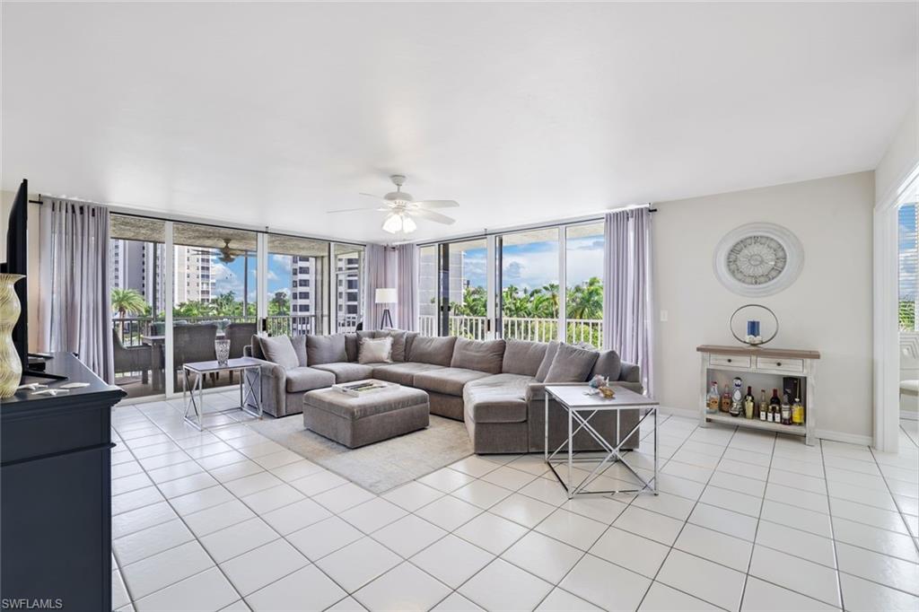 Living room with ceiling fan, light tile flooring, and a wall of windows
