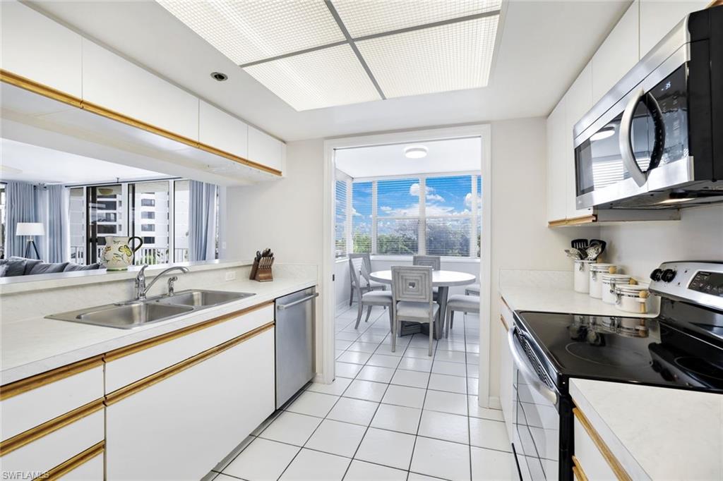 Kitchen with sink, stainless steel appliances, white cabinetry, and light tile floors