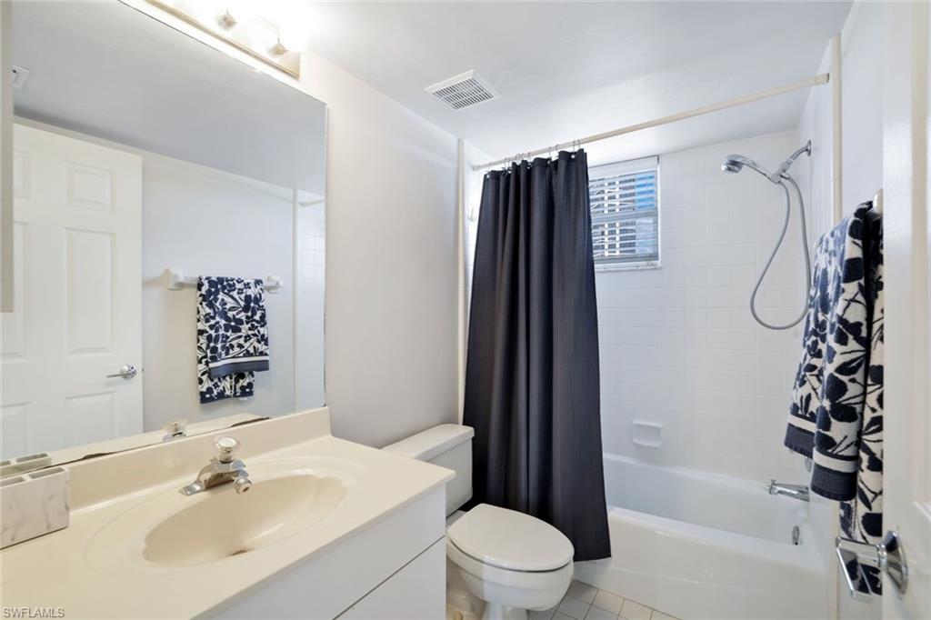 Full bathroom with oversized vanity, toilet, tile floors, and shower / tub combo