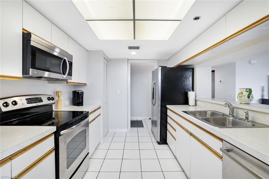 Kitchen featuring sink, light tile floors, white cabinetry, and appliances with stainless steel finishes