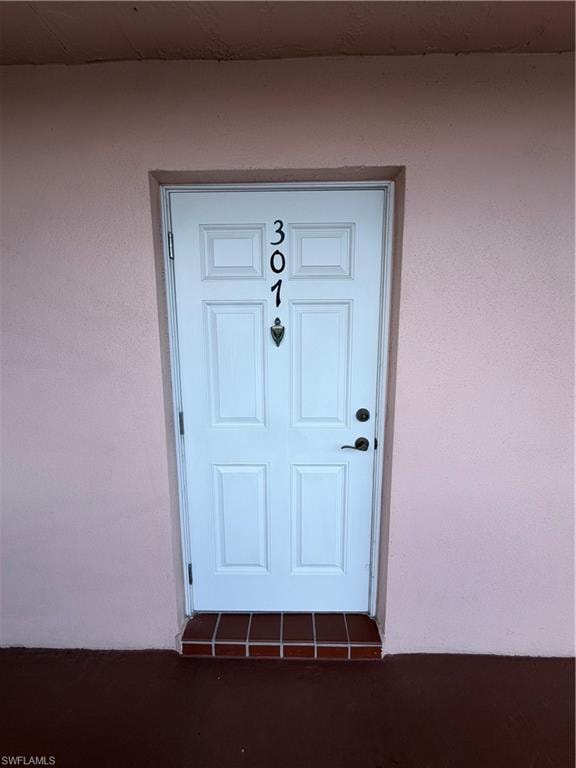White paneled entry door featuring dark hardware and a decorative knocker