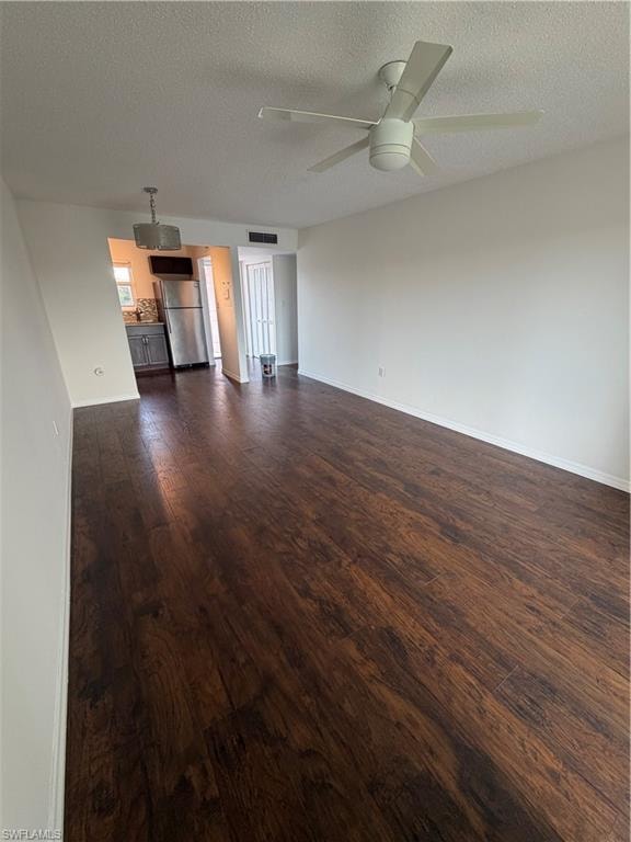 Spacious room featuring wood-finish flooring, a ceiling fan, and white walls