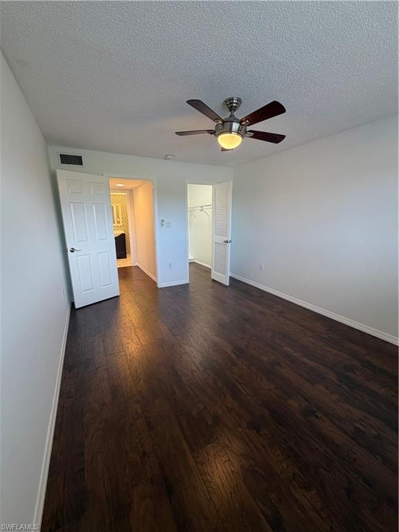Spacious room featuring dark wood-finish flooring, a ceiling fan with integrated lighting, and white paneled doors