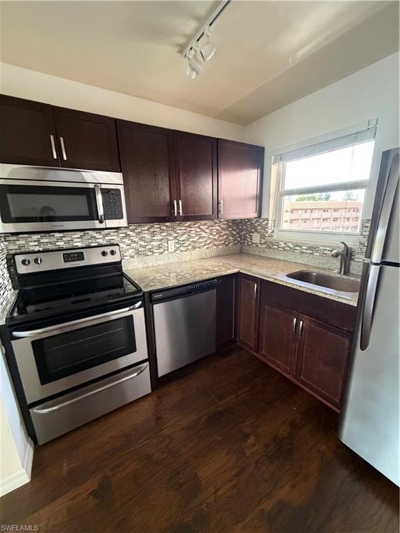 Kitchen featuring wood-finish flooring, dark wood cabinetry, stainless steel appliances, speckled countertops, and a mosaic tile backsplash