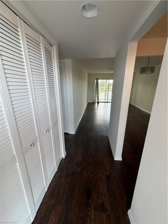 Hallway featuring wood-finish flooring, white baseboards, and bright white walls