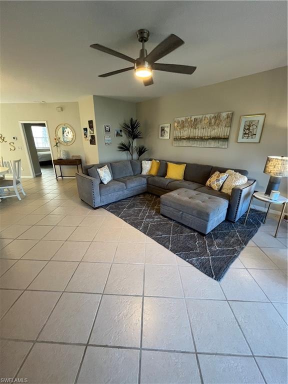 Spacious living area featuring a ceiling fan with integrated lighting, neutral wall tones, and square tile flooring