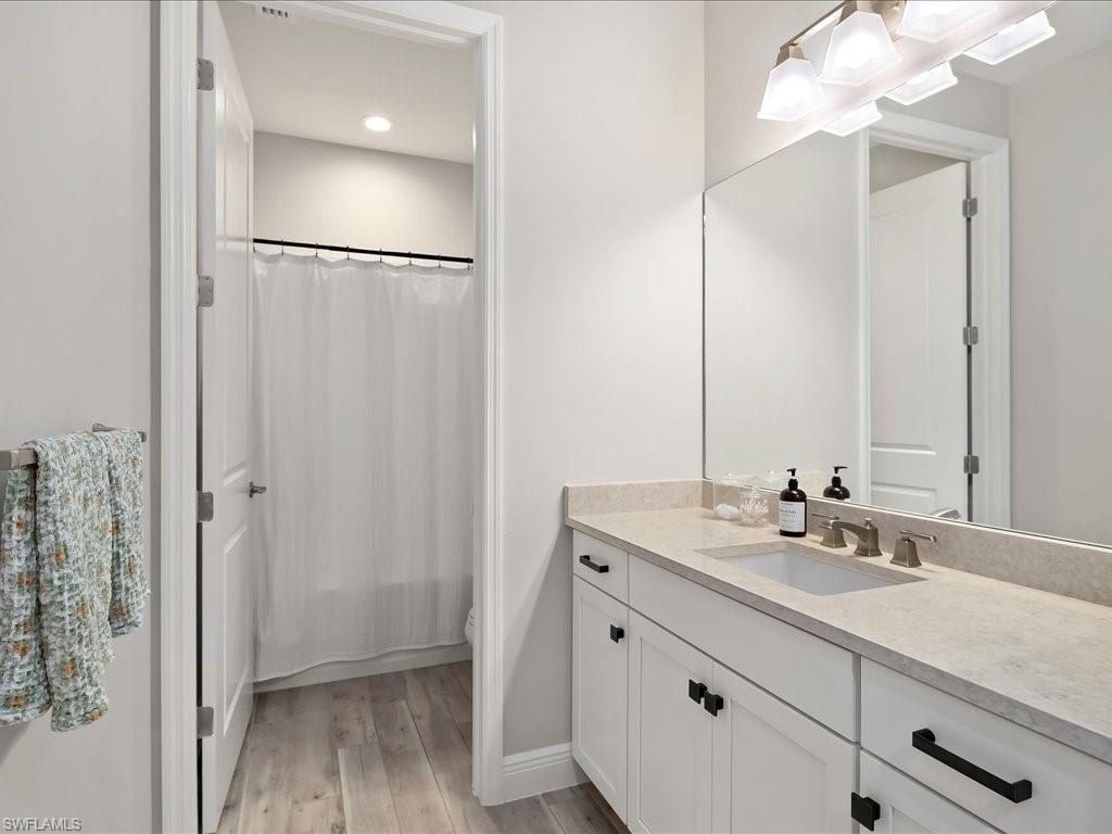 Bathroom featuring a single vanity with stone-finish countertop, undermount sink, and dark-toned hardware