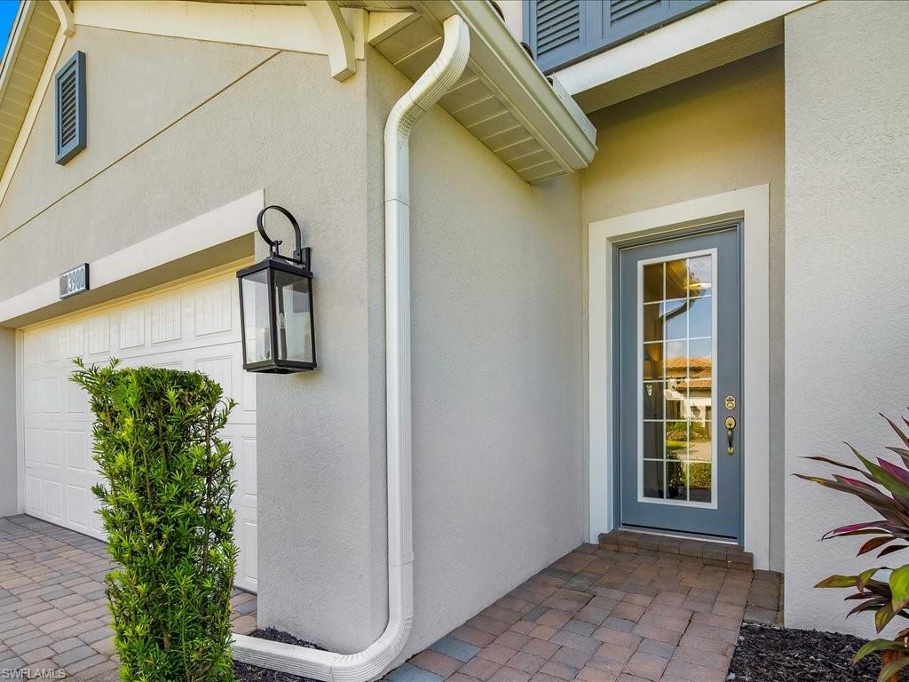 Entryway featuring a paneled glass door, exterior wall lantern, and paver walkway