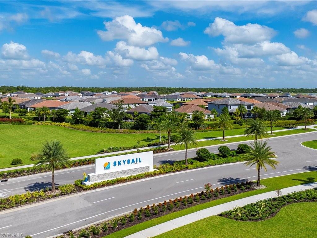 Community entrance featuring a SkySail monument sign, manicured landscaping, paved streets, and a collection of single-family homes with diverse rooflines
