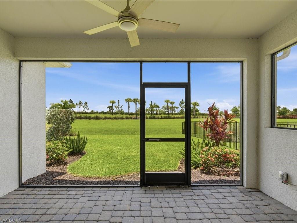 Screened patio featuring paver flooring, a ceiling fan with integrated lighting, and direct access to the landscaped yard
