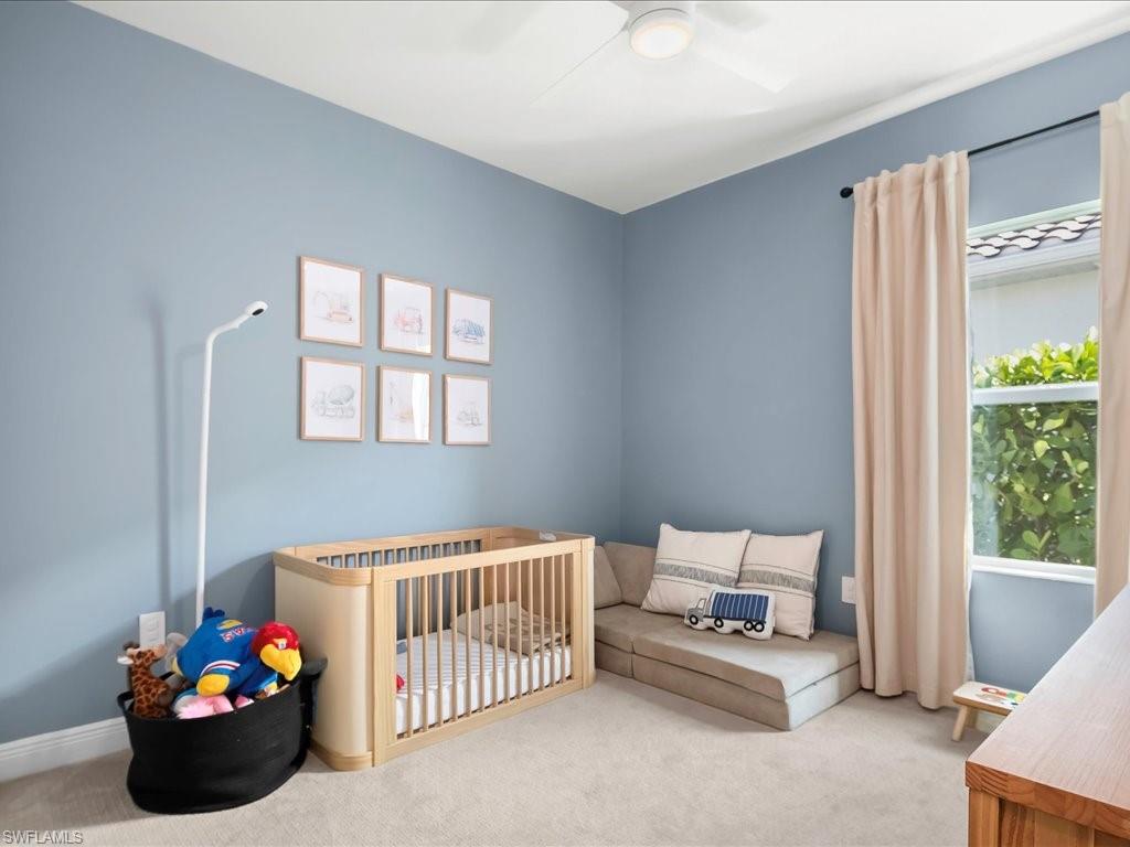 Bedroom featuring light blue walls, neutral carpet flooring, and a ceiling fan with integrated lighting