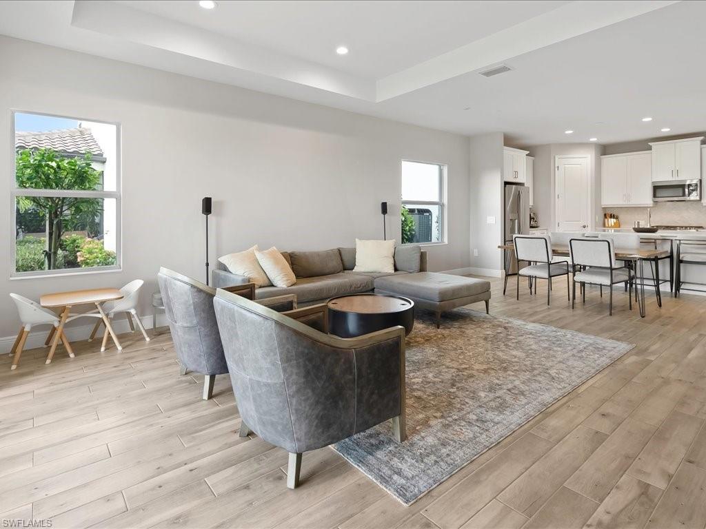 Open-concept living space featuring wood-finish flooring, recessed lighting, and a tray ceiling
