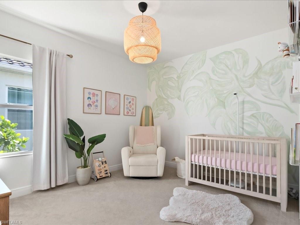 Light-filled room featuring a decorative accent wall, recessed window, light-colored carpeting, and a woven pendant light fixture