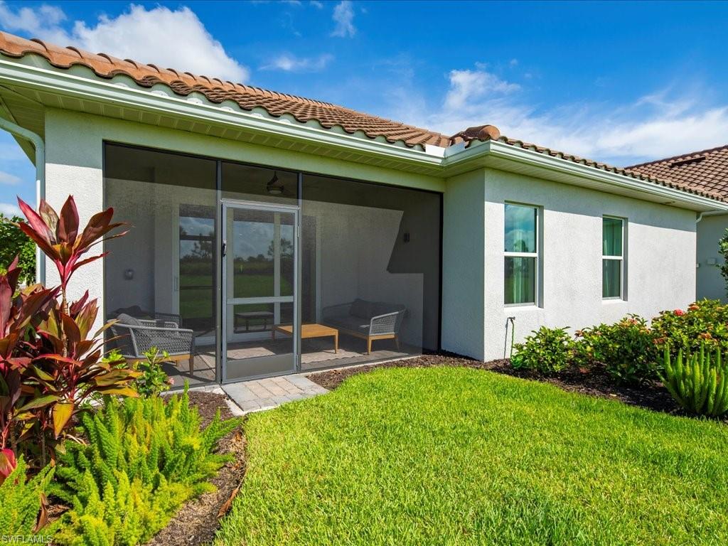 Screened patio area featuring a tiled roofline, stucco exterior, and surrounding landscaping