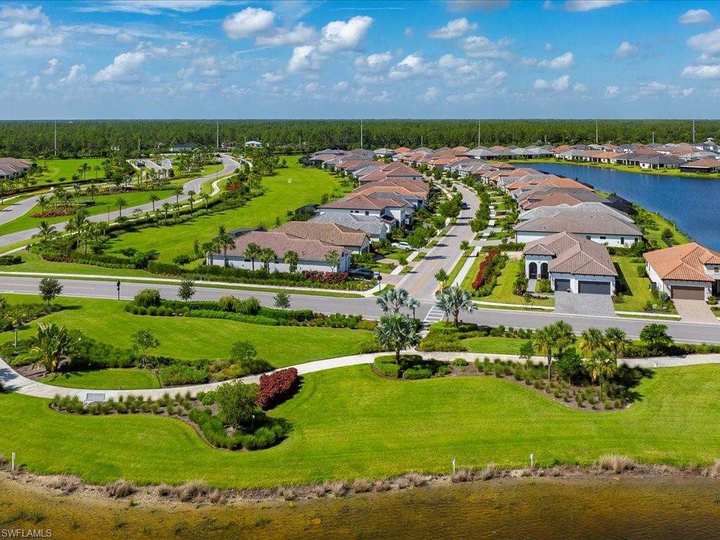 Expansive residential community featuring a paved street network, integrated sidewalks, abundant green spaces with mature landscaping, and waterfront properties along a lake