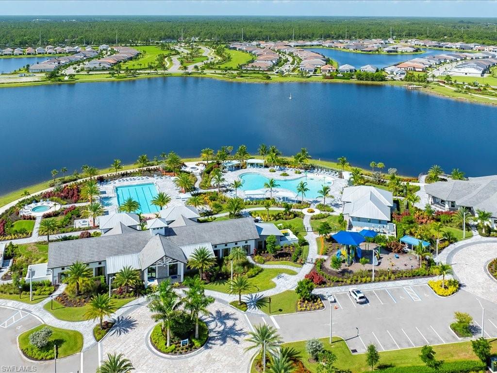 Expansive community amenities situated lakeside, featuring a multi-lane lap pool, a resort-style pool with integrated spa, and a separate aquatic play area