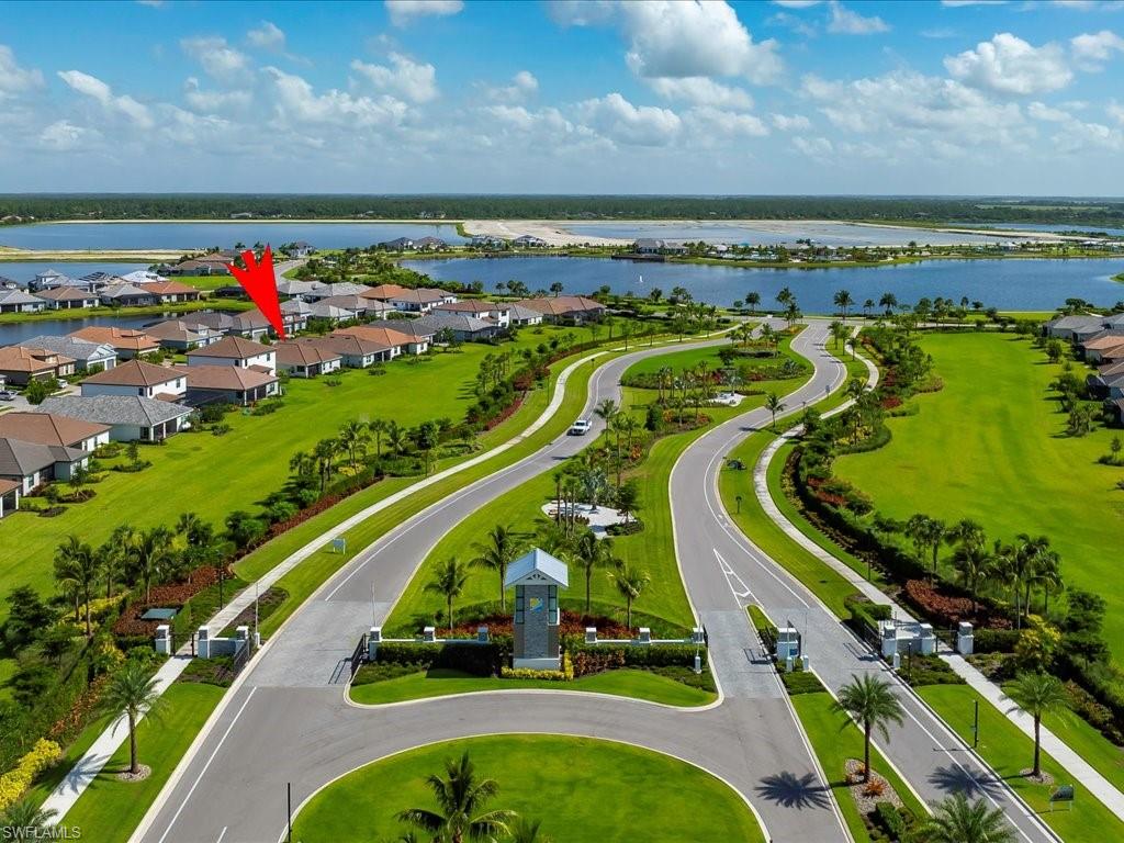 Gated community entrance featuring manicured landscaping, paved roadways, and an architectural entry structure