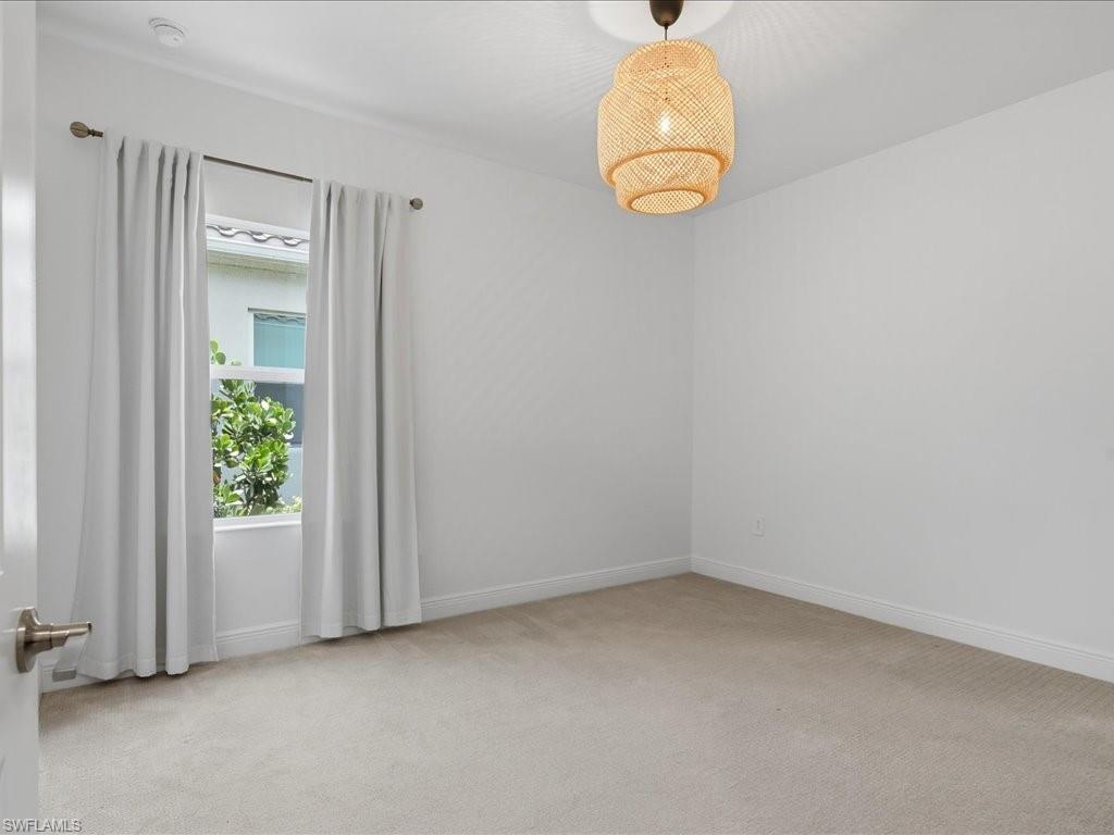 Carpeted room featuring a double-hung window with drapery and a woven pendant light fixture