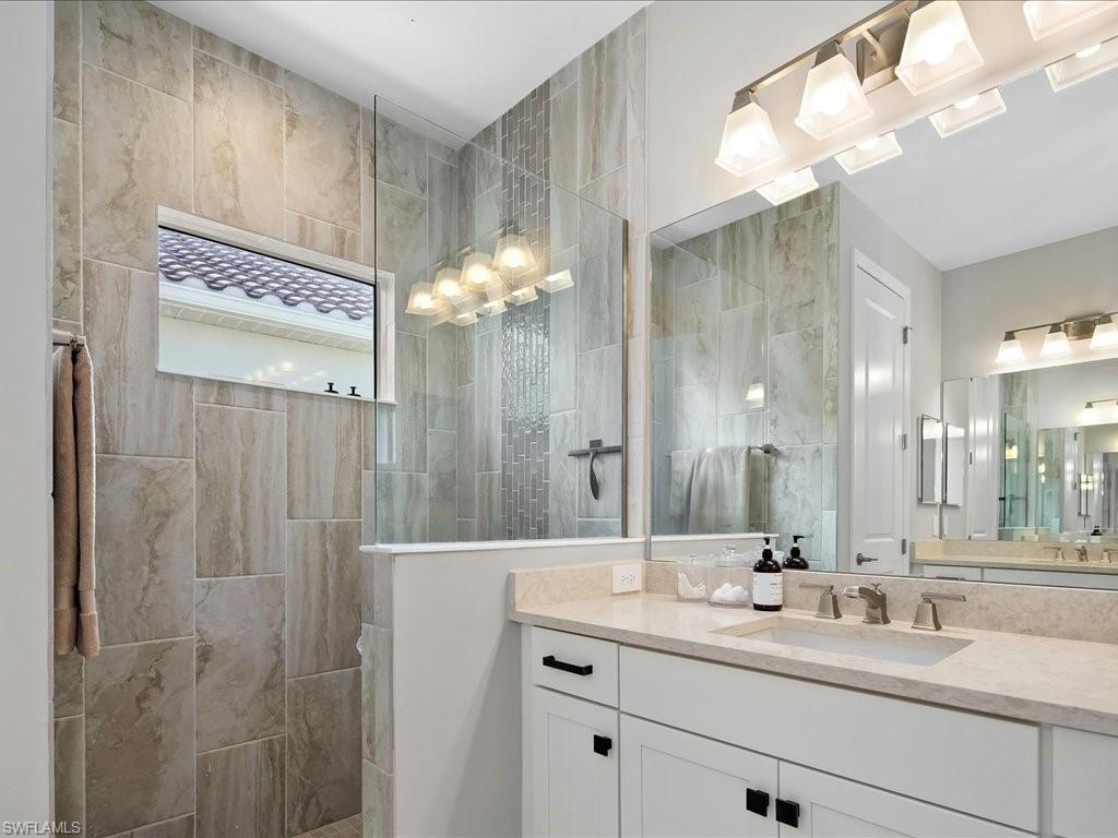Bathroom featuring a spacious walk-in shower with a glass enclosure, light-toned tile work, and a horizontal window
