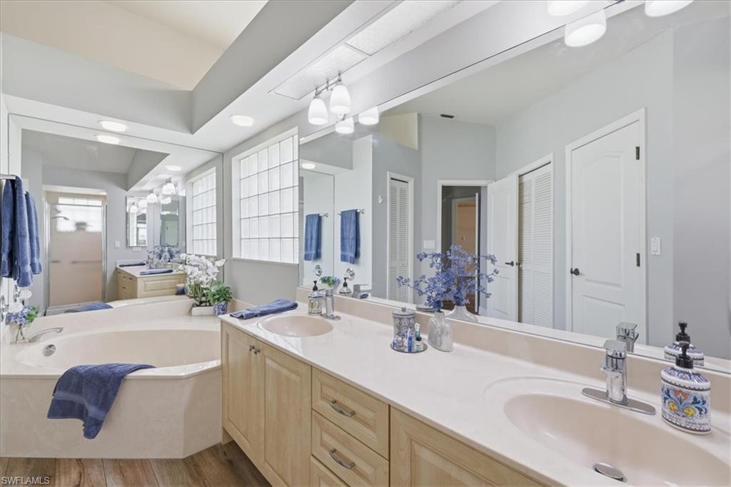 Bathroom featuring a wood-finish floor and a dual vanity with light cabinetry and integrated sinks