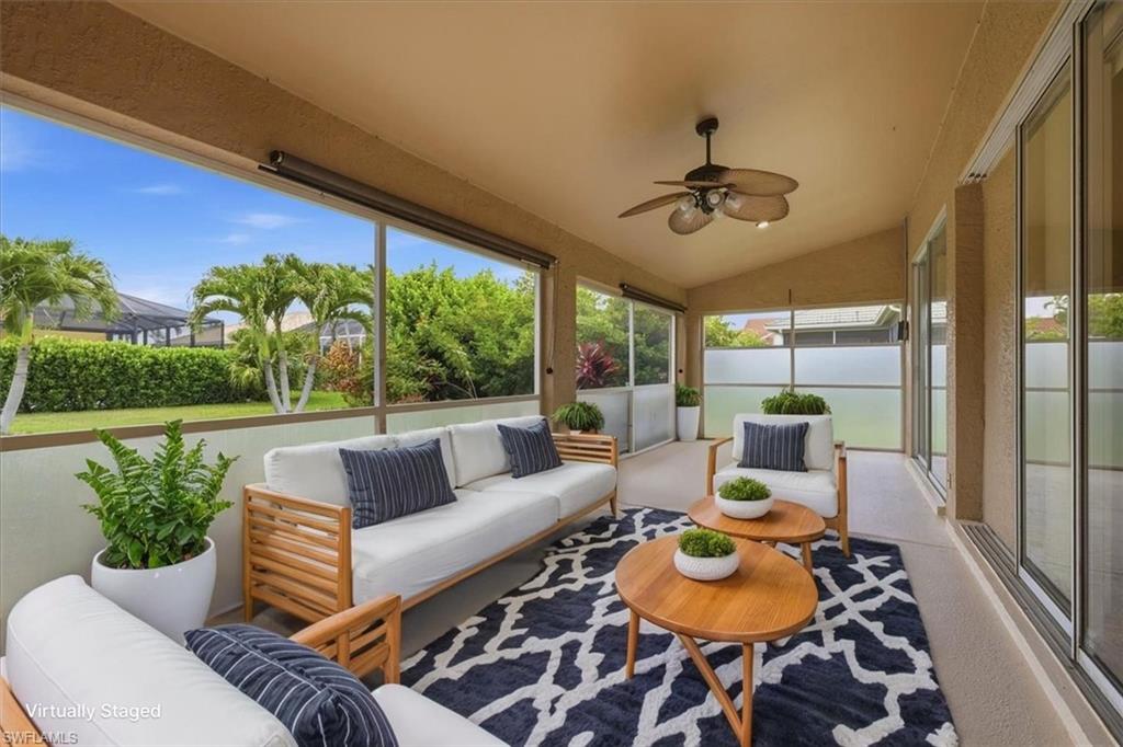 *VIRTUALLY STAGED* Expansive screened lanai featuring a vaulted ceiling with a ceiling fan, concrete flooring, and sliding glass door access