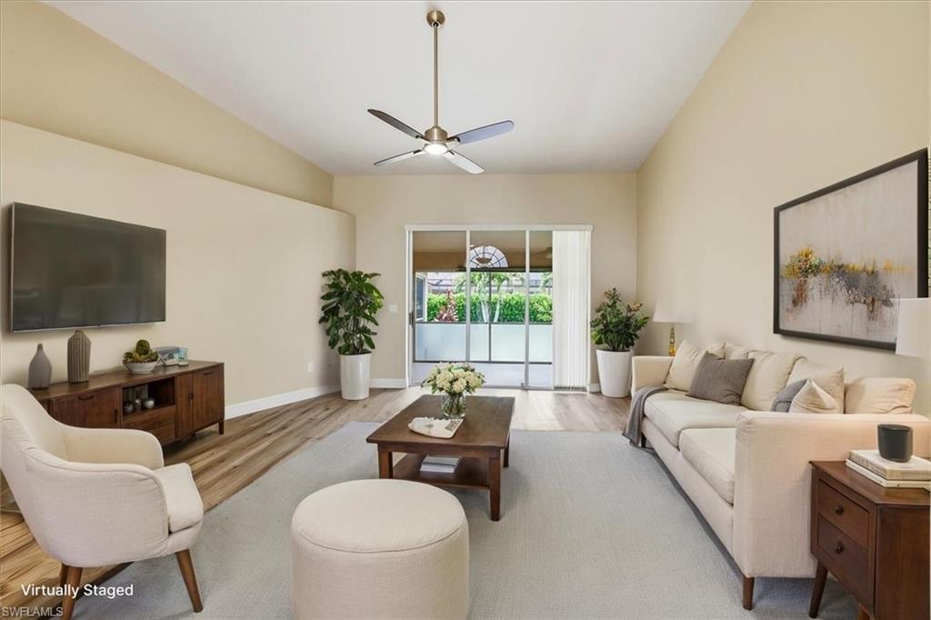 *VIRTUALLY STAGED* Vaulted ceilings enhance this living space featuring wood-finish flooring, a ceiling fan with integrated lighting, and direct access to an outdoor area via sliding glass doors
