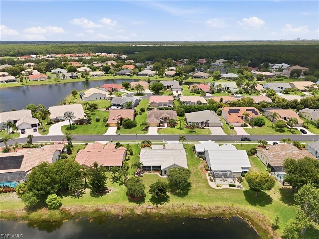 Residential neighborhood featuring water frontage, paved roads, established landscaping, and mature trees