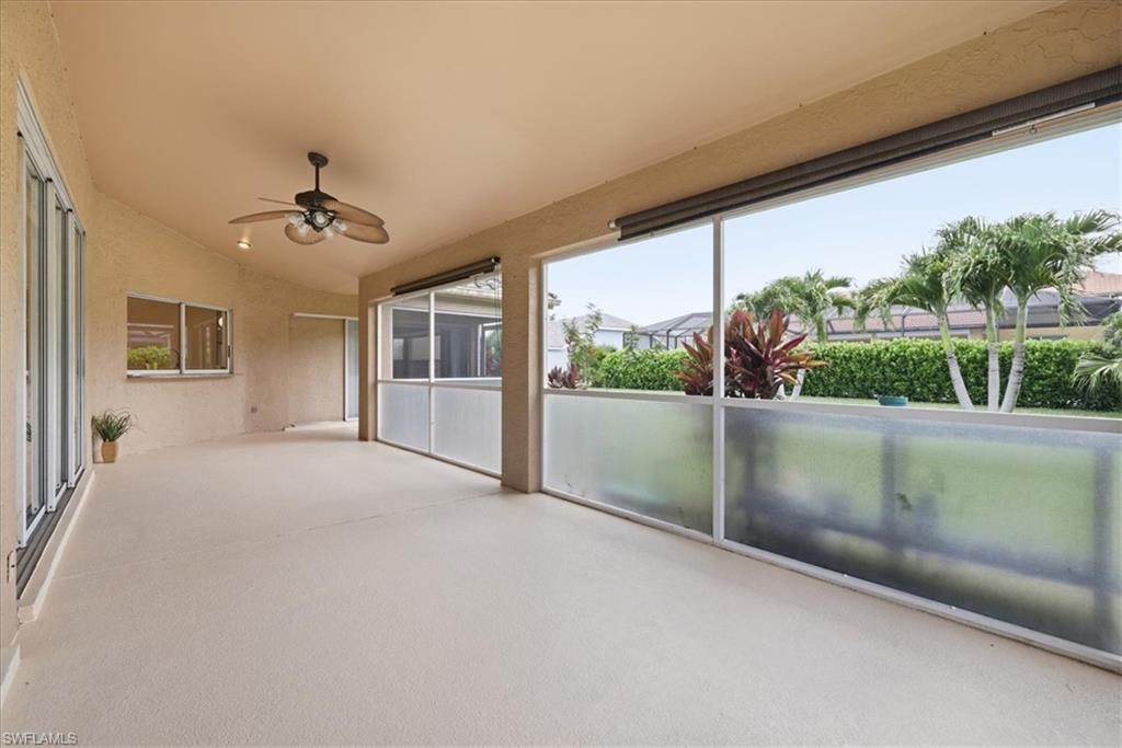 Expansive screened patio featuring a textured floor, a ceiling fan with integrated lighting, and multiple sliding glass doors