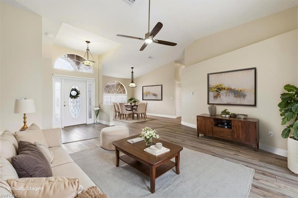 *VIRTUALLY STAGED* Vaulted ceilings above a bright entry with a decorative glass door and sidelights, complemented by wood-finish flooring