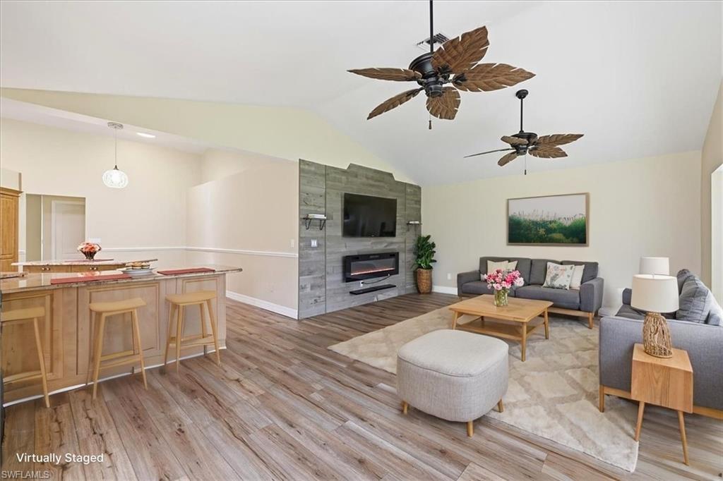 *VIRTUALLY STAGED* Vaulted ceiling great room featuring wood-finish flooring and a stone-style accent wall with an integrated fireplace and media console