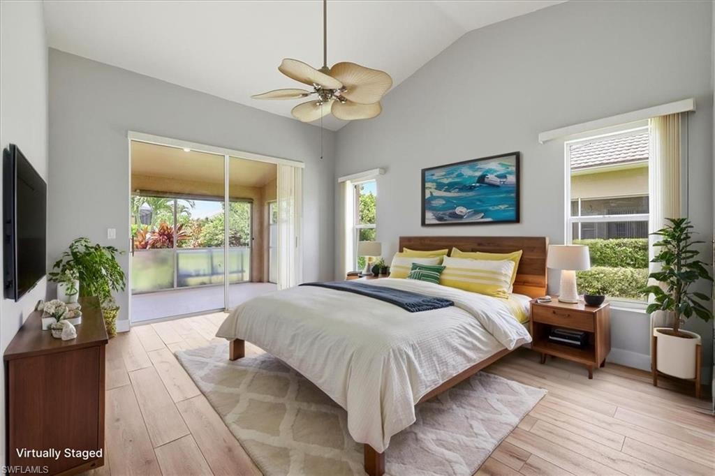*VIRTUALLY STAGED* Vaulted ceiling bedroom with light-toned wood-finish flooring, a ceiling fan, and large sliding glass doors opening to a covered patio