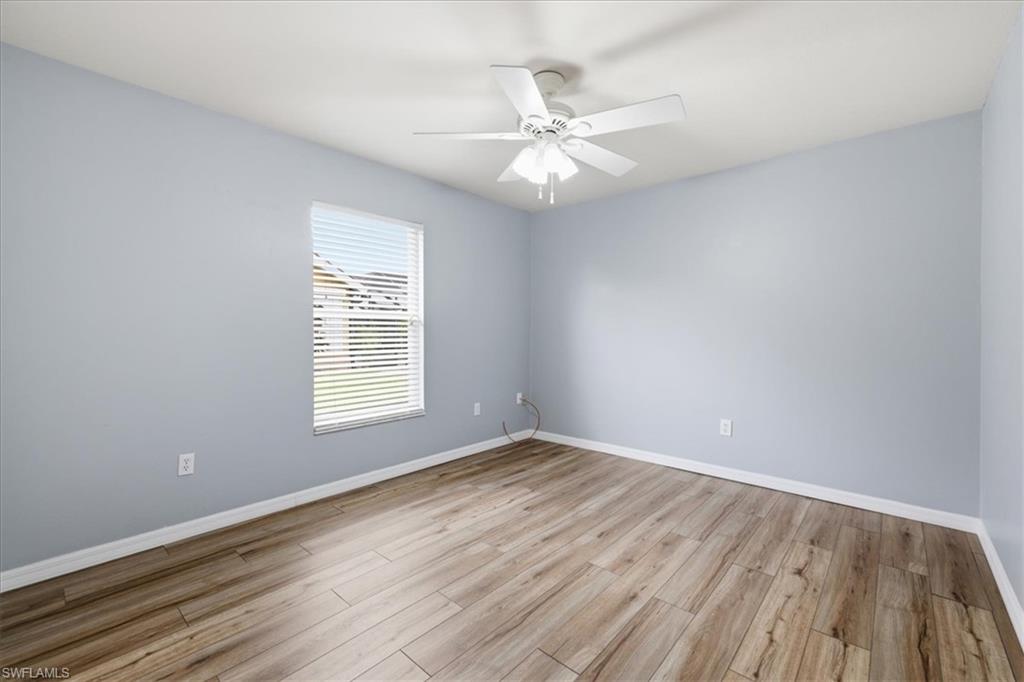 Room featuring wood-finish flooring, a ceiling fan with integrated lighting, and a single window with horizontal blinds