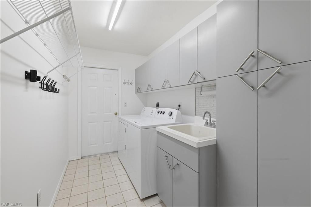 Laundry room with extensive gray cabinetry, utility sink, tile flooring, and integrated wire shelving