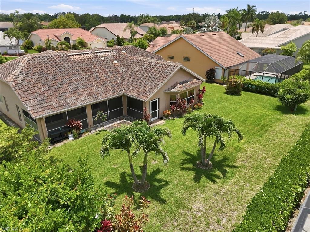 Expansive backyard featuring a manicured lawn, two mature palm trees, and established perimeter hedges