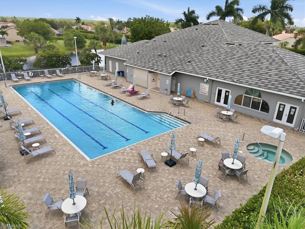 Outdoor amenity area featuring a rectangular swimming pool with lane markers, an adjacent spa, and extensive paver decking