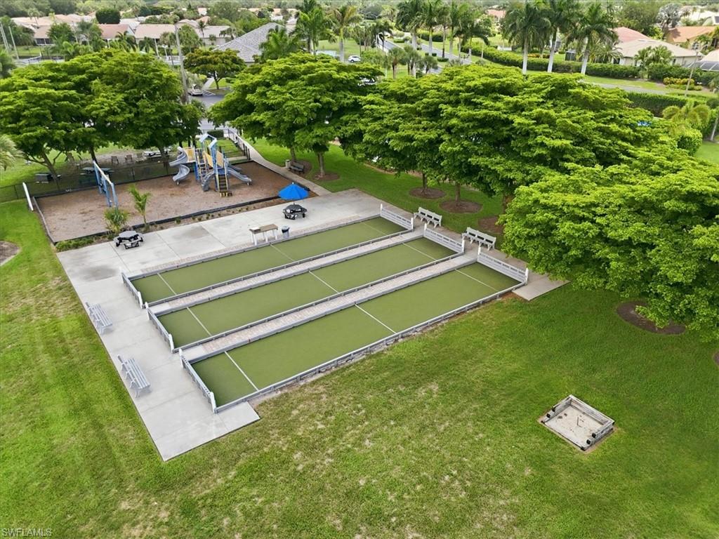 Recreational area featuring three bocce ball courts, a playground with slides, swings, and climbing structures, and expansive green spaces