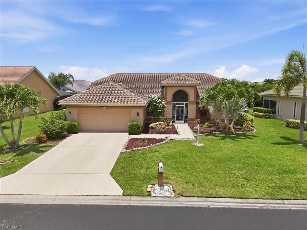 Mediterranean-style residence featuring a tile roof, arched entryway, and mature tropical landscaping