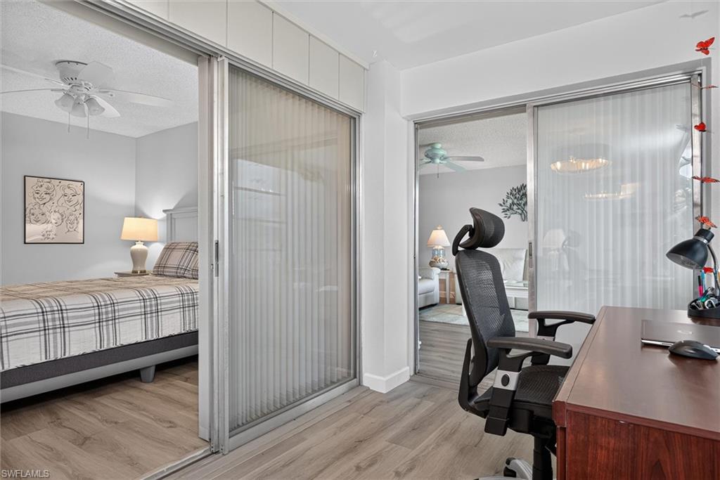 Light-toned wood-finish flooring extends throughout these interior spaces, featuring sliding privacy panels with vertical blinds