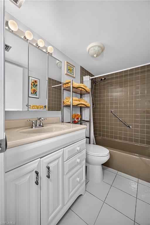 Full Guest Bathroom featuring a white vanity with a tan countertop and integrated sink, a built-in tub with brown wall tiling, and white floor tiling